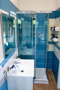 W wyłożonej niebieskimi kafelkami łazience znajduje się umywalka i prysznic. w obiekcie b&b binario nove e tre quarti w Agropoli