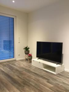 ein Wohnzimmer mit einem Flachbild-TV auf einem weißen Entertainment-Center in der Unterkunft Ferienwohnung Calla in Erfurt