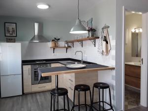 a kitchen with a sink and two bar stools at Casita La Finca I in Breña Baja