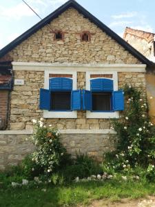 Una casa de piedra con persianas azules. en Casa Anca Cheile Nerei, en Socolari