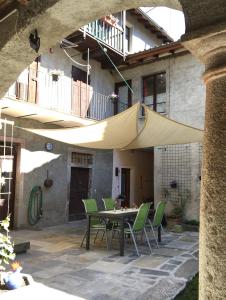 a patio with a table and chairs under a tan umbrella at Ca' di Pincia in Astano +25 photos