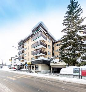 ein Gebäude an der Seite einer Straße mit einem Baum in der Unterkunft Unique Alpic style apartment in the heart of Davos in Davos