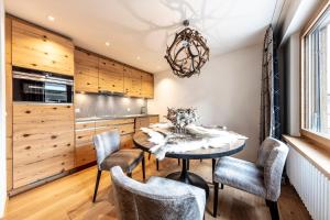 - une cuisine avec des placards en bois, une table et des chaises dans l'établissement Unique Alpic style apartment in the heart of Davos, à Davos