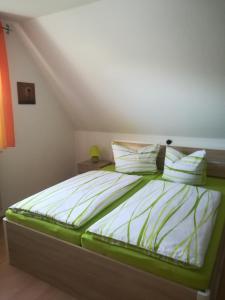 Cama con sábanas y almohadas verdes y blancas en Ferienwohnung Düne, en Ostseebad Sellin