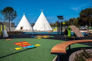 ein Spielplatz mit Spielgeräten und ein paar Tipis in der Unterkunft Kazela Apartments in Medulin