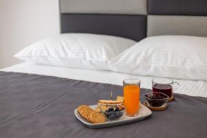 a tray of food on a bed with two glasses of orange juice at Villa Apartments Kordić in Kaštela