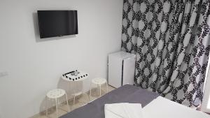 a room with a bed and a tv and stools at Vila Raelma in Eforie Nord