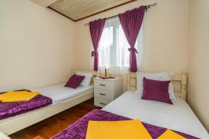 2 Betten in einem Zimmer mit lila und gelber Bettwäsche in der Unterkunft Guest House Luna in Virpazar