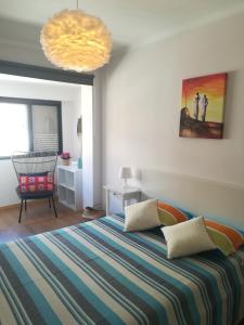 a bedroom with a bed and a chair and a chandelier at Paula's Beach Apartment in Costa da Caparica