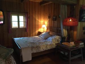 1 dormitorio con 1 cama y 1 mesa con lámpara en Cozy Log Cabin near Faaker See en Ledenitzen