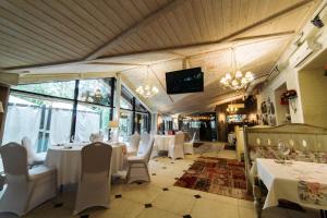 a restaurant with white tables and chairs and a tv at SPA Hotel Veranda in Smolensk