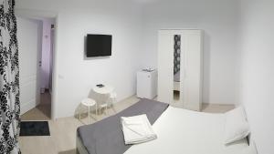 a white bedroom with a bed and a tv at Vila Raelma in Eforie Nord
