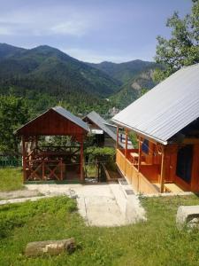 a building with a pavilion with mountains in the background at Guest House Ilia in Borjomi