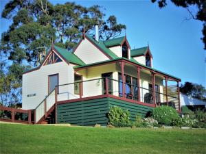 una grande casa bianca con tetto verde di Maple Ridge Cottages a Dumbalk