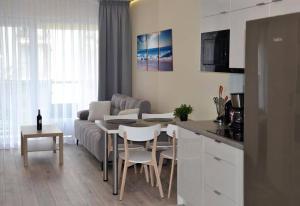 a kitchen and living room with a couch and a table at Apartament Srebrny z garażem in Kołobrzeg