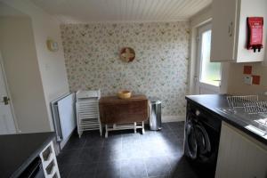 a kitchen with a table and a dishwasher at Maggies Cottage in Bushmills