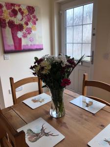 um vaso de flores sentado em cima de uma mesa de madeira em 41 Larchwood Drive Holiday Home em Inverness