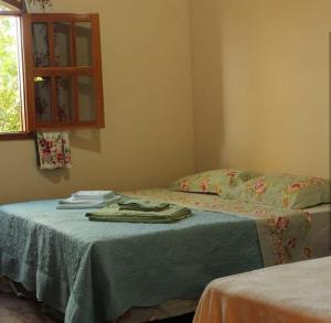 a bedroom with a bed with a green blanket and a window at Jardim das orquídeas in Mucugê