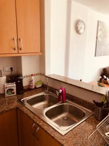 eine Küchentheke mit Spüle und eine Uhr an der Wand in der Unterkunft Apartamento Solmar in Peñíscola