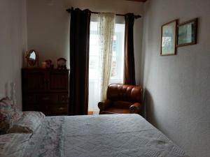 a bedroom with a bed and a chair and a window at Pandora in Faja Grande