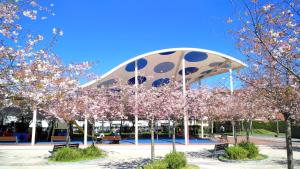 a pavilion with flowering trees in front of a building at Kaixo Family in Zarautz
