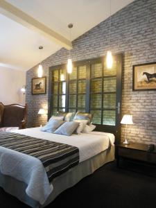 a bedroom with a large bed and a brick wall at Logis Hôtel Le Glacier in Orange