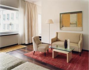 a living room with a couch and a table and a chair at Hotel Greif in Bolzano
