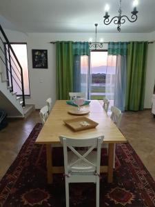 ein Esszimmer mit einem Holztisch und grünen Vorhängen in der Unterkunft Azóia Pool&Garden in Azoia