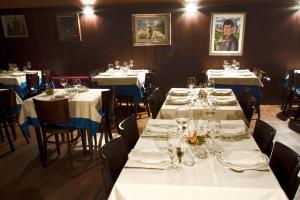 a dining room with tables and chairs with white tablecloths at Hotel Restaurante Casa Pipo in Tuña