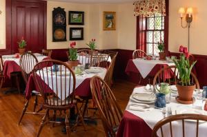 a dining room with tables with red tablecloths at Candleberry Inn on Cape Cod in Brewster