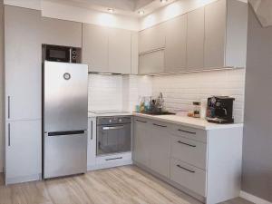 a kitchen with white cabinets and a refrigerator at Apartament Arkadia Rossa in Augustów