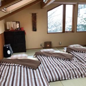a room with three beds and a dresser and windows at ガーデンハウス Mako Land in Toyama