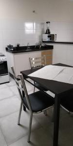 a kitchen with a black table and chairs in it at RESIDENCIA CIDADE VERDE 2, SINTA-SE EM CASA. in Maringá