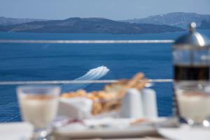 a table with a plate of food and a boat in the water at Ambition Suites in Oia