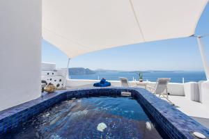 a swimming pool with a blue and white pool umbrella at Ambition Suites in Oia
