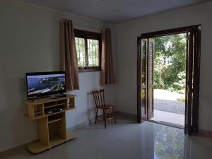 uma sala de estar com uma televisão e uma porta de vidro deslizante em Residencial Gurtler 209 em Gramado