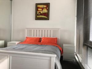 メルボルンにあるEPIC Private Apartmentのベッドルーム1室(白いベッド1台、オレンジ色の枕付) +5枚の写真