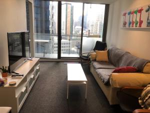 メルボルンにあるEPIC Private Apartmentのソファとテーブルのあるリビングルーム