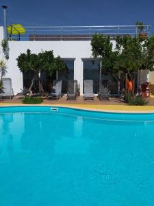 uma grande piscina azul com cadeiras e um edifício em Casas do Ardila em Santo Amador