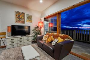 a living room with a couch and a flat screen tv at A Room With a View in Kaikoura