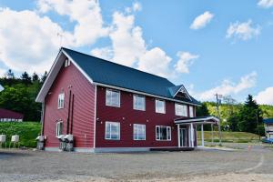 a large red barn with a black roof at Hotel Hanafuji Inn in Furano