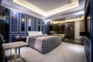 um quarto com paredes azuis, uma cama e uma banheira em OUGE Motel - Fengshan em Kaohsiung