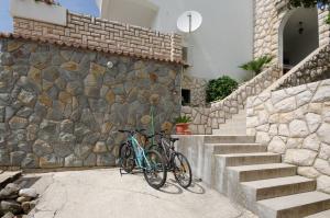 Un par de bicicletas estacionadas junto a una pared de piedra. en Apartments Zdenka en Lopar