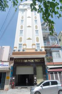 een groot wit gebouw met een auto voor de deur bij Khách sạn Ngọc Thương in Quy Nhon