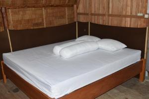 łóżko z białymi poduszkami na górze w obiekcie Tanjung Kalemo Resort w mieście Batudaka