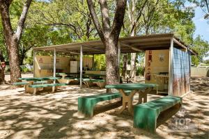 a picnic shelter with green picnic tables and benches at Riverview Tourist Village in Katherine