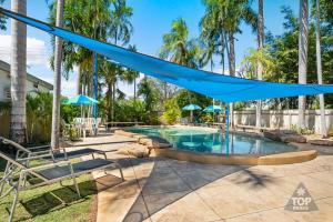 a swimming pool with a blue hammock over it at Riverview Tourist Village in Katherine