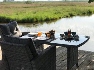 una mesa con comida y bebidas en una terraza junto a un río en Paleis Noordeinde, en Grootschermer