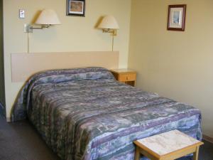 a hotel room with a bed and two tables at Hotel Motel Bon Accueil in Rivière-la-Madeleine