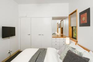 a white bedroom with a bed and a tv at Byron Getaway @the Crest in Byron Bay +22 photos